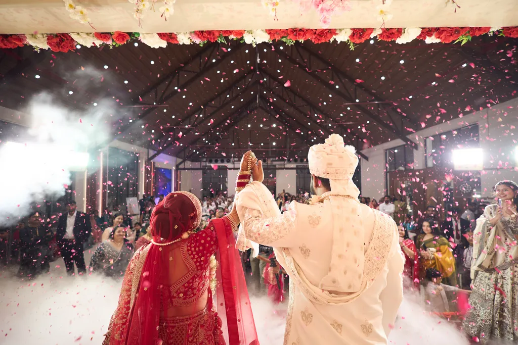 Jaimala on the wedding stage with guests cheering and flower petals in the air at a Varanasi wedding